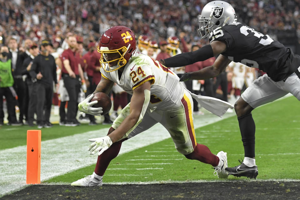 Washington Football Team running back Antonio Gibson (24) scores a touchdown around Las Vegas Raiders cornerback Brandon Facyson (35) during the second half of an NFL football game, Sunday, Dec. 5, 2021, in Las Vegas. (AP Photo/David Becker)