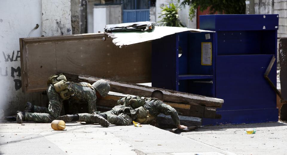 Government soldiers battling Moro National Liberation Front rebels crawl behind a barricade put up by the rebels in downtown Zamboanga city