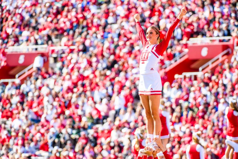 An Indiana cheerleader is lifted high in front of a big crowd Oct. 16, 2021, during the Indiana-Michigan State football game at Memorial Stadium in Bloomington.