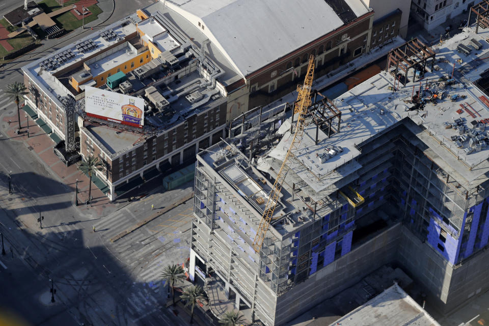 One of two large cranes from the Hard Rock Hotel construction collapse is seen hanging over the edge above Canal Street in this aerial photo after crashing down, after being detonated for implosion in New Orleans, Sunday, Oct. 20, 2019. The Saenger Theater, seen in top of frame, appears undamaged from the operation. (AP Photo/Gerald Herbert)