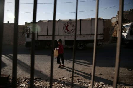 A boy walks near a Red Crescent and United Nations aid convoy in the rebel held besieged town of Douma, eastern Ghouta in Damascus, Syria October 19, 2016. REUTERS/Bassam Khabieh