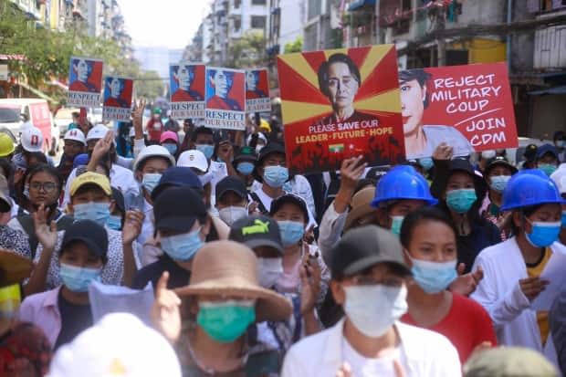 Anti-coup protesters hold up images of deposed leader Aung San Suu Kyi as they gather in Yangon, Myanmar, Friday, Mar. 5, 2021. Demonstrators defy growing violence by security forces and stage more anti-coup protests ahead of a special UN Security Council meeting on the country's political crisis. (The Associated Press - image credit)