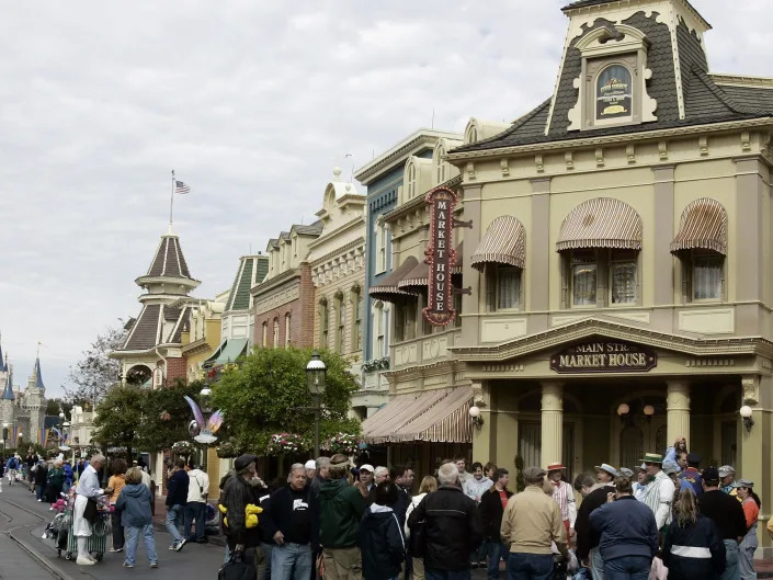 Street with old fashioned store fronts and crowds of people.