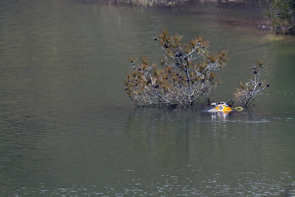 A diver's helmet is seen as he searches in a lake for female bodies near the village of Xiliatos outside of capital Nicosia, Cyprus, Friday, April 26, 2019. Cyprus police are intensifying a search for the remains of more victims at locations where an army officer _ who authorities say admitted to killing five women and two girls _ had dumped their bodies. (AP Photo/Petros Karadjias)