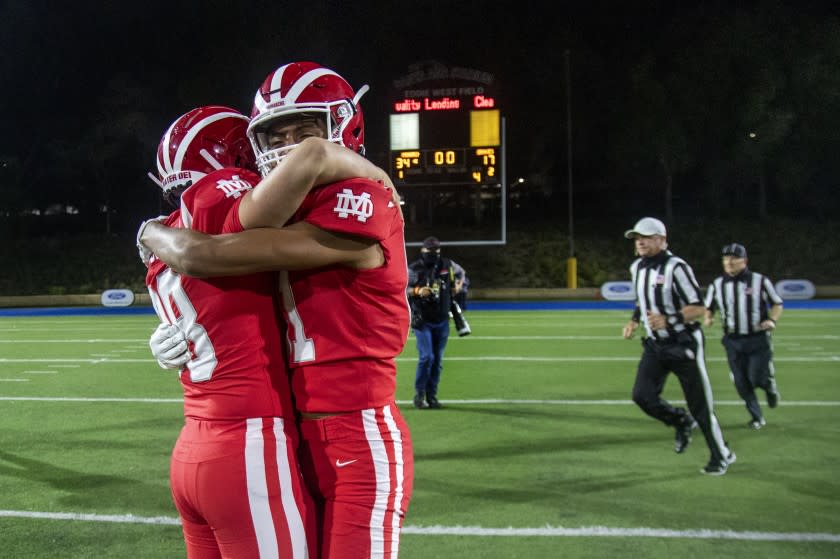 SANTA ANA, CA - APRIL 17, 2021: Mater Dei Jack Ressler (88), left, and Isaiah Lopez (81) hug after their teams 34-17 win over St John Bosco at Santa Ana Stadium on April 17, 2021 in Santa Ana, California.(Gina Ferazzi / Los Angeles Times)