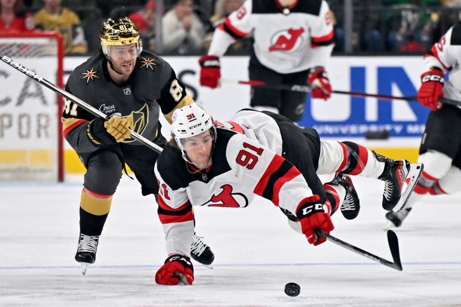 New Jersey Devils center Dawson Mercer (91) dives to reach the puck against Vegas Golden Knights right wing Jonathan Marchessault (81) during the first period of an NHL hockey game Sunday, March 17, 2024, in Las Vegas. (AP Photo/David Becker)