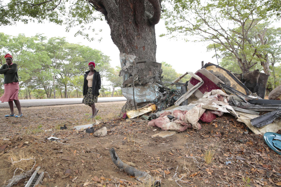 Women walk by the scene of a bus crash in Rusape about 170 kilometres east of the capital Harare, Thursday, Nov. 8, 2018. A head-on collision between two buses has killed 47 people, where road accidents are common due to poor roads and bad driving. (AP Photo/Tsvangirayi Mukwazhi)