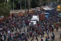 Honduran migrants are blocked by Guatemalan soldiers and police from advancing toward the US border, also affecting cargo trucks on the highway in Vado Hondo, Guatemala, Monday, Jan. 18, 2021. The roadblock was strategically placed at a chokepoint on the two-lane highway flanked by a tall mountainside and a wall leaving the migrants with few options. (AP Photo/Sandra Sebastian)