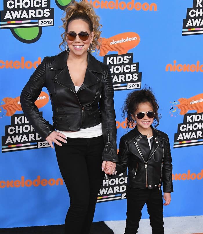 Mariah holds Monroe's hand as they wear matching leather jackets, black jeans, and aviator sunglasses