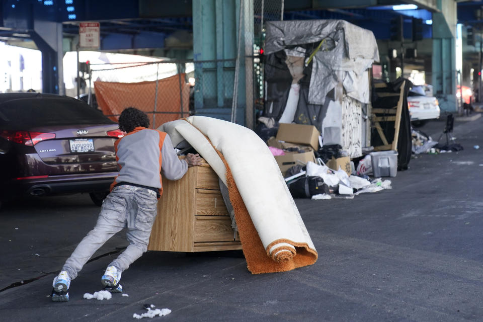 A man pushes items while a homeless encampment is being cleaned up in San Francisco, Tuesday, Aug. 29, 2023. Cities across the U.S. are struggling with and cracking down on tent encampments as the number of homeless people grows, largely due to a lack of affordable housing. Homeless people and their advocates say sweeps are cruel and costly, and there aren't enough homes or beds for everyone. (AP Photo/Jeff Chiu)