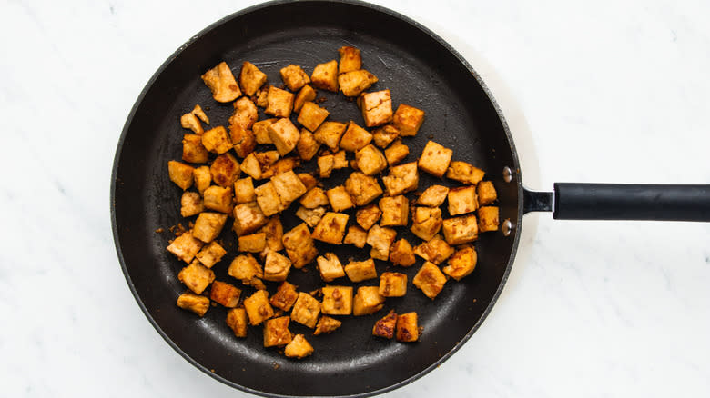 Cubed tofu frying in pan