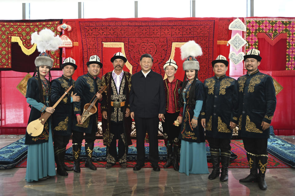 In this photo released by China's Xinhua News Agency, Chinese President Xi Jinping, center, poses for a photo with performers of the Manas, a cultural epic of the Kyrgyz people, at the Museum of the Xinjiang Uyghur Autonomous Region in Urumqi in northwestern China's Xinjiang Uyghur Autonomous Region, Wednesday, July 13, 2022. (Xie Huanchi/Xinhua via AP)