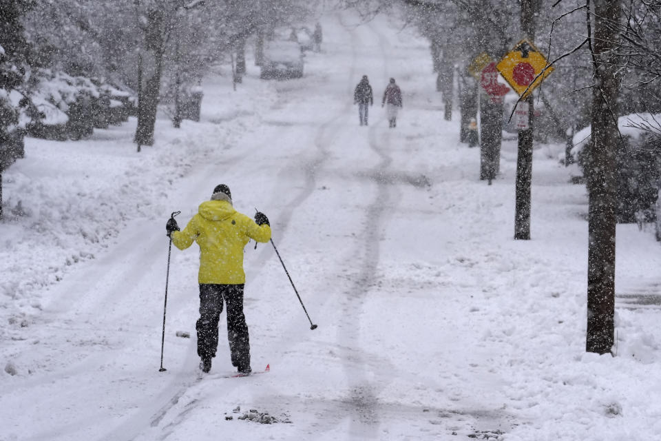 Nelson Taylor, of Providence, R.I., left, uses cross-country skis while making his way along a residential street, Tuesday, Feb. 13, 2024, in Providence. Parts of the Northeast have been hit by a coastal storm that's dumping snow and packing strong winds in some areas, while others aren't getting as much snow as anticipated. (AP Photo/Steven Senne)