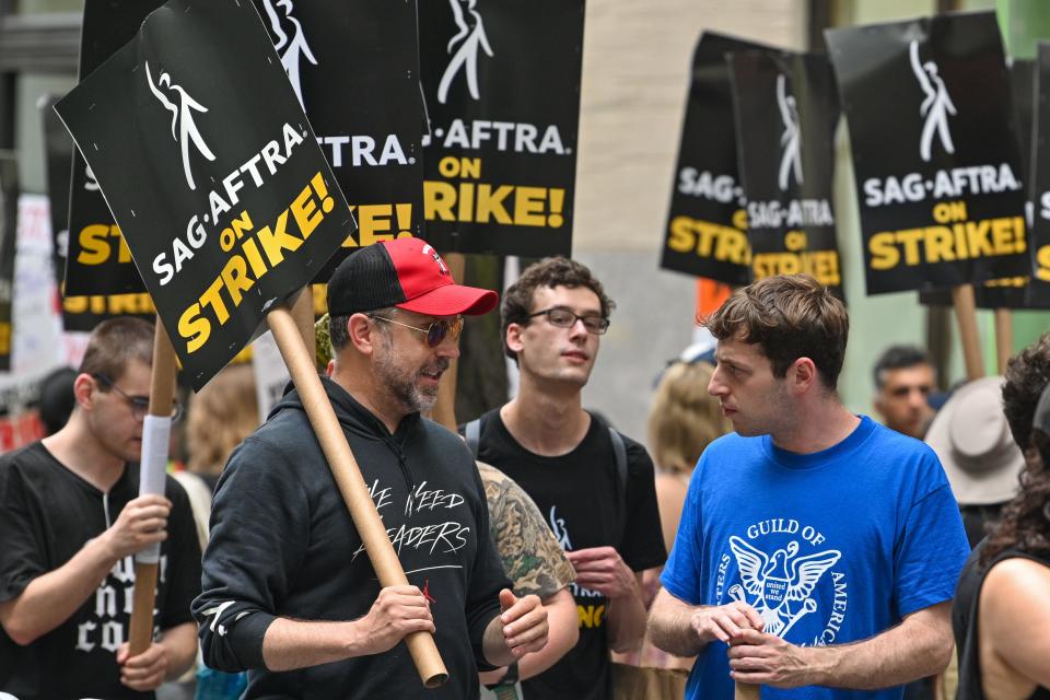 Jason Sudeikis and Alex Edelman are seen walking the picket line with striking WGA and SAG-AFTRA members outside NBC Rockefeller Center on July 14, 2023 in New York City.