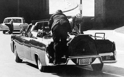 President John F. Kennedy slumps down in the back seat of the Presidential limousine as it speeds along Elm Street toward the Stemmons Freeway overpass in Dallas after being fatally shot. [Nov. 22, 1963 file photo] - Credit: AP Photo/James W. "Ike" Altgens