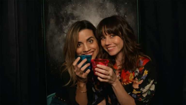 Natalie Morales and Linda Cardellini cheers in a photo booth
