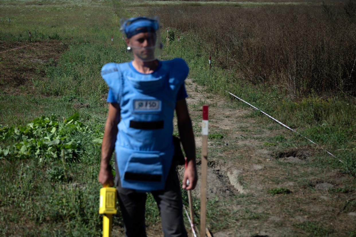 A man dress in protective gear watches as U.S. Secretary of State Antony Blinken tours farmland in Yahidne, Ukraine (AP)