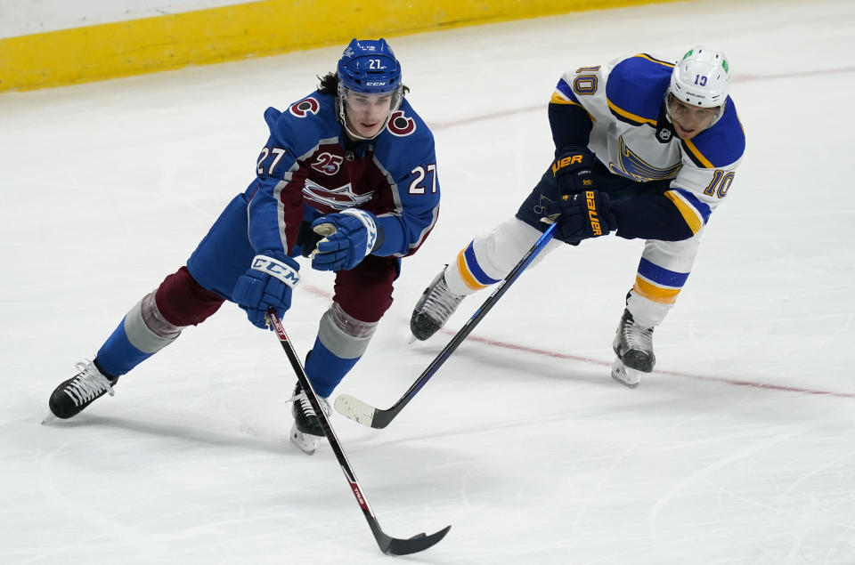 Colorado Avalanche defenseman Ryan Graves, left, reaches out to pick up the puck as St. Louis Blues center Brayden Schenn defends in the first period of an NHL hockey game Friday, Jan. 15, 2021, in Denver. (AP Photo/David Zalubowski)