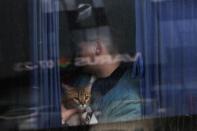 <p>Un joven sujeta en brazos a su gato sentado junto a la ventanilla de un autobús preparado para salir de Kiev. (Foto: Umit Bektas / Reuters).</p> 