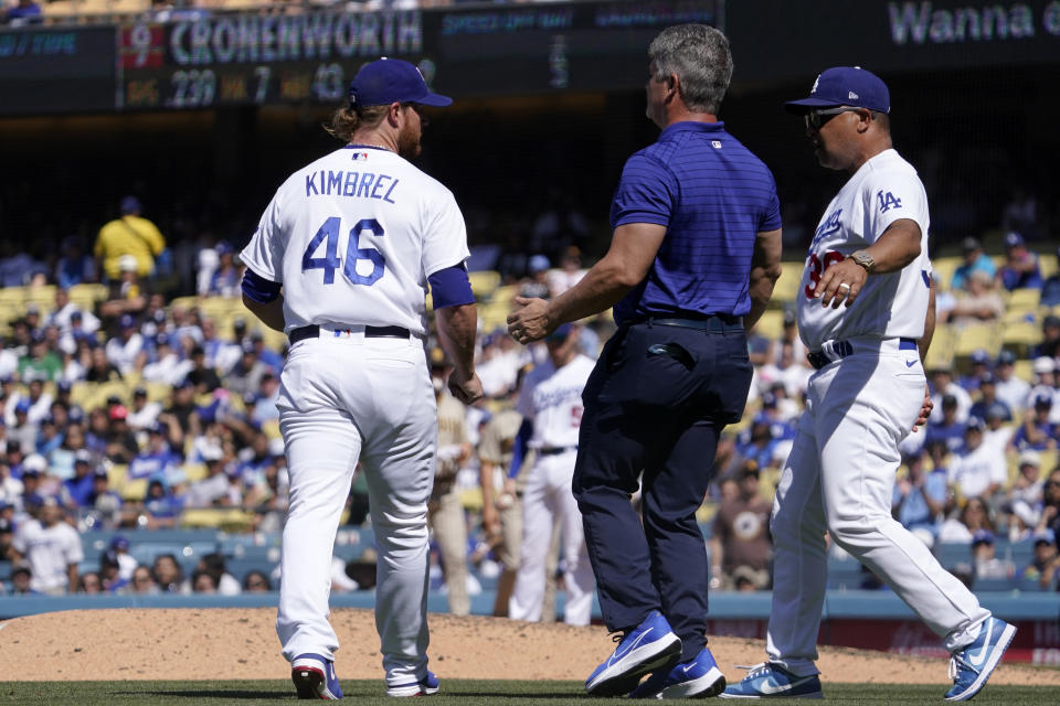 Los Angeles Dodgers manager Dave Roberts, right, runs out along with a trainer to check on relief pitcher Craig Kimbrel, left, after Kimbrel was struck by a ball hit by San Diego Padres' Jake Cronenworth during the ninth inning of a baseball game Sunday, July 3, 2022, in Los Angeles. (AP Photo/Mark J. Terrill)