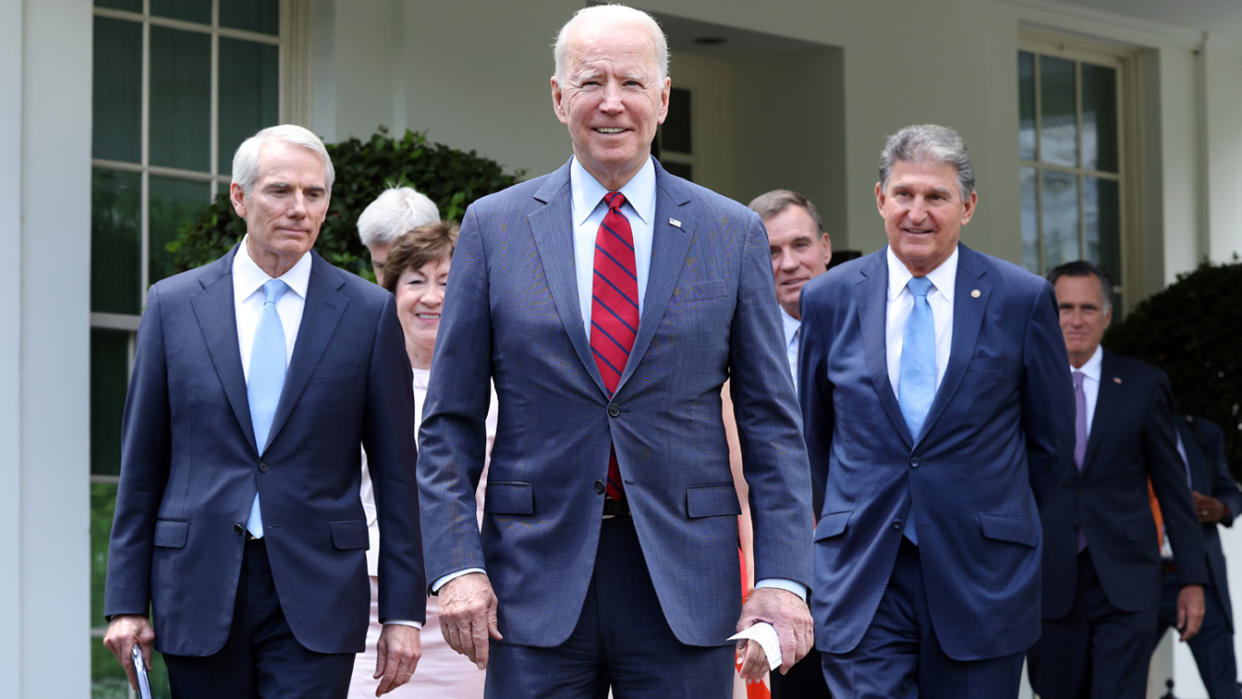 President Biden walks in front of a group of Senators