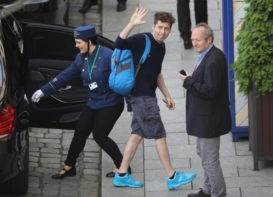 Sam Altman waving while stepping out of a car into a Hotel in Germany.