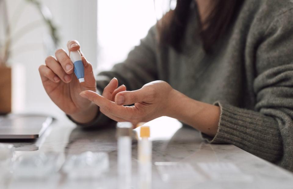 cropped shot of young woman using blood test kit at home while doing health check and consultation online home finger prick blood test