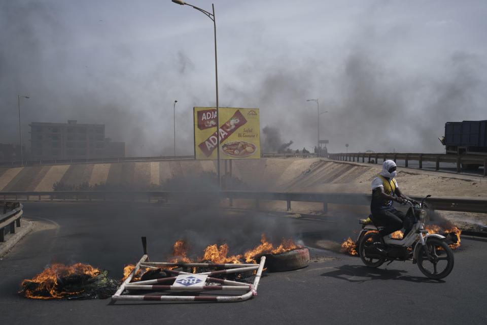 A man drives his motorcycle past tires set on fire during clashes between demonstrators and riot policemen at a neighborhood in Dakar, Senegal, Friday, June 2, 2023. Clashes between police and supporters of Senegalese opposition leader Ousmane Sonko left nine people dead, the government said Friday, with authorities issuing a blanket ban on the use of several social media platforms in the aftermath of the violence (AP Photo/Leo Correa)