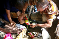 A father helps his son to buy used shoes at the used-clothes market in Baghdad, Iraq, Tuesday, Oct. 20, 2020. Iraq is in the throes of an unprecedented liquidity crisis, as the cash-strapped state wrestles to pay public sector salaries and import essential goods while oil prices remain dangerously low. (AP Photo/Khalid Mohammed)