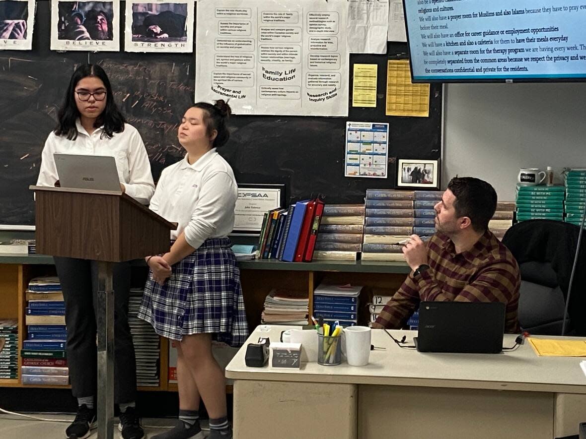 Two students, Allyssa Artale, left and Myeisha Tso, right, present their research and ideas on the issue of homelessness to their Grade 12 Assumption high school class. Teacher John Talerico, far right, invited a city councillor to hear them. (Nav Nanwa/CBC - image credit)