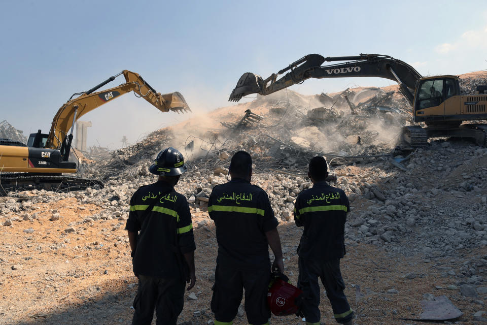 A rescue team watch diggers tackle the removal of debris from this week's massive explosion in the port of Beirut, Lebanon, Friday, Aug. 7, 2020. Three days after a massive explosion rocked Beirut, killing over a hundred people and causing widespread devastation, rescuers are still searching for survivors and the government is investigating what caused the disaster. (AP Photo/Thibault Camus)