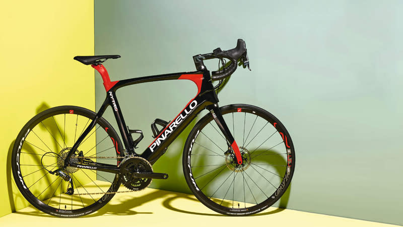  A black and red Pinarello Nytro electric road bike stands in the corner of a yellow/green room 