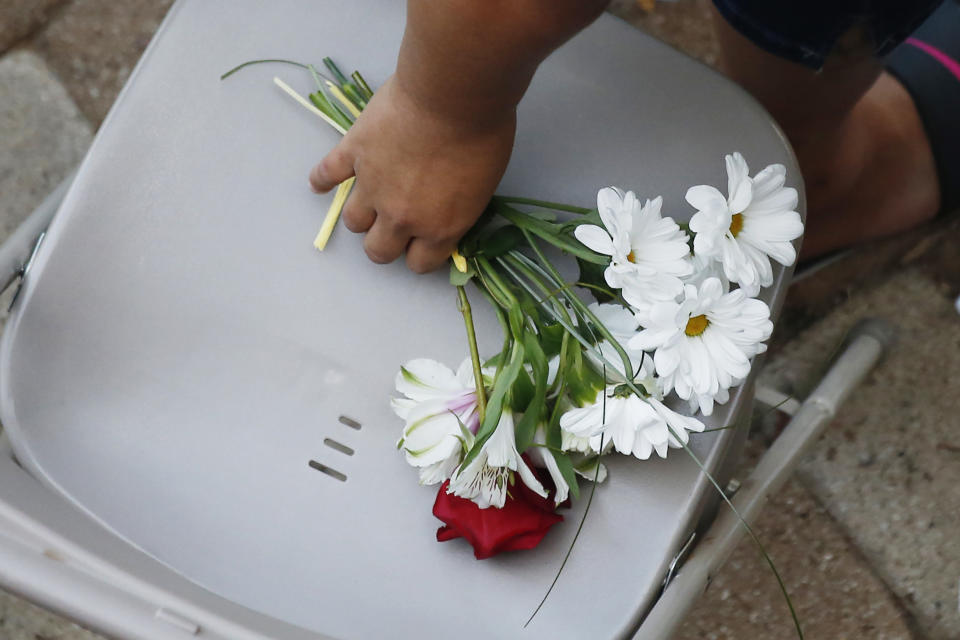 A woman reaches for a bunch of flowers during a memorial service for the victims of Saturday's shootings at a memorial service Sunday, Sept. 1, 2019, in Odessa, Texas. (AP Photo/Sue Ogrocki)