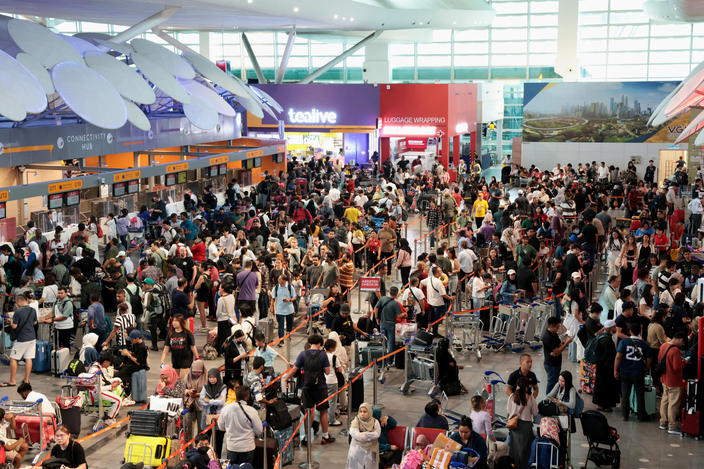 Hundreds of passengers wait to be manually checked in at Kuala Lumpur International Airport.