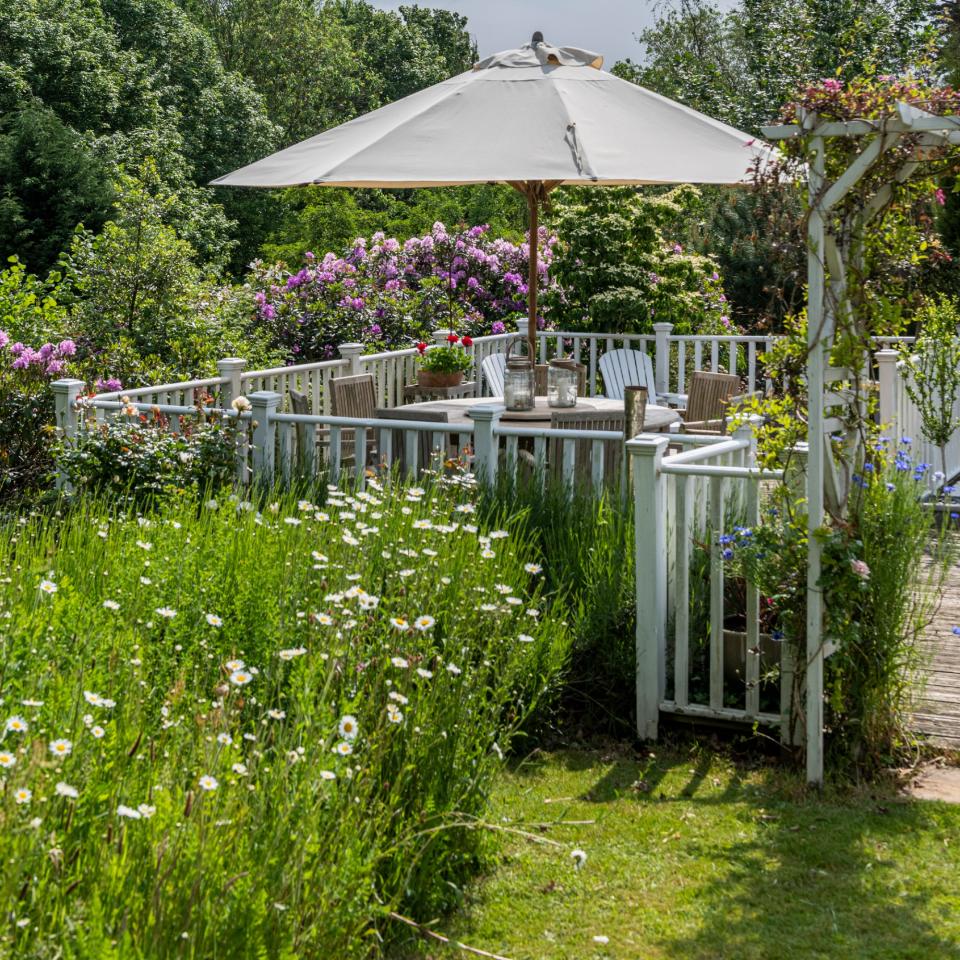 A blooming garden with a garden furniture and parasol set