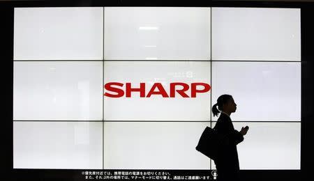 A woman walks past the Sharp Corp's Logo at a train station in Tokyo March 6, 2013. REUTERS/Yuya Shino