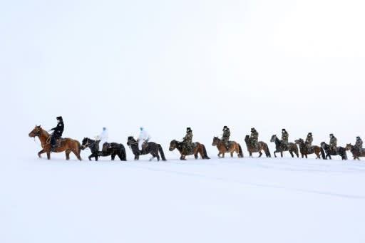 Police officers wearing protective face masks ride horses through the snow to visit residents of remote Altay in China's Xinjiang region and promote awareness of the novel coronavirus