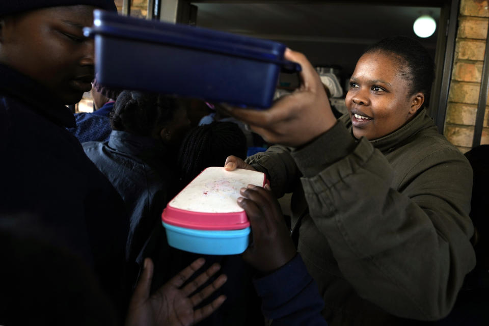 Lebohang Mphuthi distributes meals to children during a lunch break at the Omar H.S. Ebrahim Primary School in Lotus Gardens, west of Pretoria, South Africa, Tuesday, July 25, 2023. South Africa's official unemployment rate of 33% is the highest in the world, and economists say it's even higher at 42% if you count those who have given up looking for work and have dropped off unemployment systems. (AP Photo/Themba Hadebe)