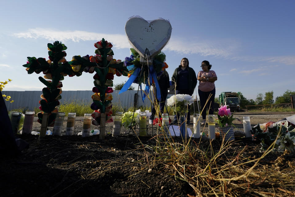 Dolientes miran un monumento conmemorativo improvisado en el sitio donde las autoridades hallaron a docenas de personas muertas en un tractocamión abandonado, el miércoles 29 de junio de 2022, en San Antonio. (AP Foto/Eric Gay)