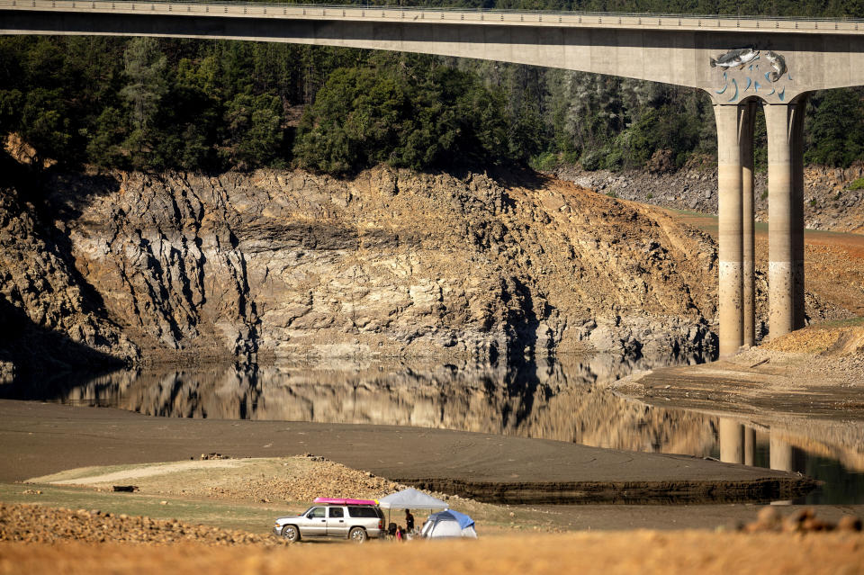 A family camps on a dry riverbed at Shasta Lake on Monday, May 24, 2021, in Shasta Trinity National Forest, Calif. At the time of this photo, the reservoir was at 45 percent of capacity and 52 percent of its historical average. (AP Photo/Noah Berger)