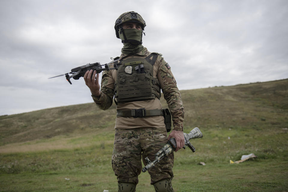 A volunteer soldier holds up a drone used to release explosives at a training area outside Kyiv, Ukraine, Saturday, Aug. 27, 2022. Some volunteers signed up to join a Chechen unit that fights alongside the Ukrainian military. Fighters from Chechnya, the Russian republic in the North Caucasus, are participating on both sides of the conflict in Ukraine, with pro-Kyiv volunteers loyal to Dzhokhar Dudayev, the late Chechen leader who headed the republic's drive for independence from Russia. (AP Photo/Andrew Kravchenko)