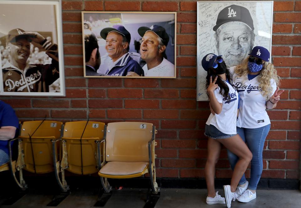 A pair of Dodgers fans pose for pictures beside a display of former Dodgers manager Tommy Lasorda.