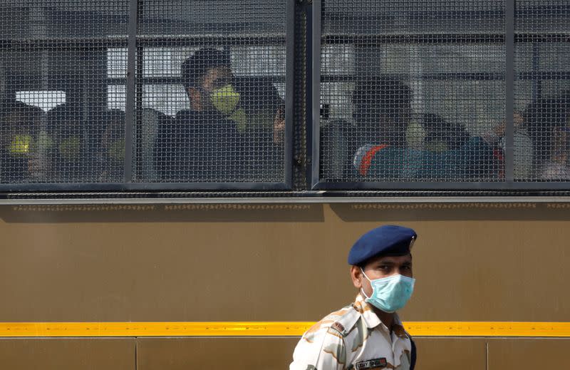 Indian nationals sitting in a bus are transported out of Indira Gandhi International Airport following their evacuation from the Chinese city of Wuhan