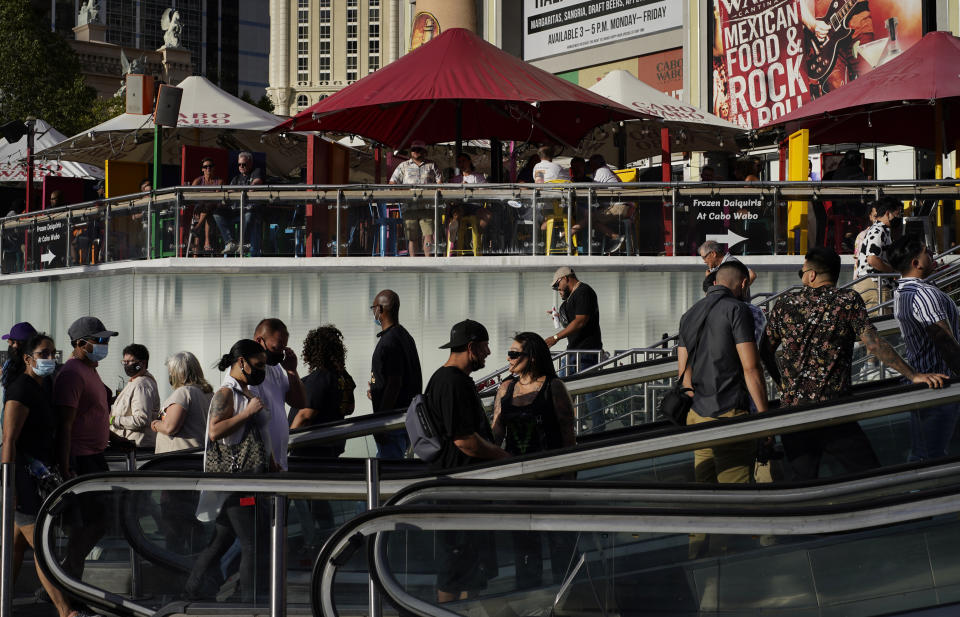 People walk as others dine on the Las Vegas Strip, Saturday, April 24, 2021, in Las Vegas. Las Vegas is bouncing back to pre-coronavirus pandemic levels, with increases in airport passengers and tourism. (AP Photo/John Locher)