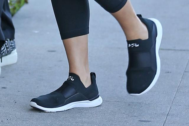 Chrissy Teigen Goes Sporty-Casual in Bandeau, Biker Jacket, Leggings and  APL Sneakers