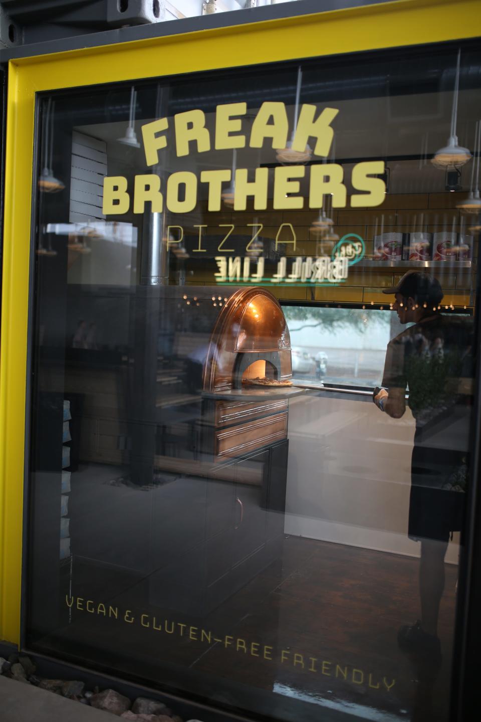 A man places a pizza in the oven at Freak Brothers Pizza at the Churchill in downtown Phoenix.