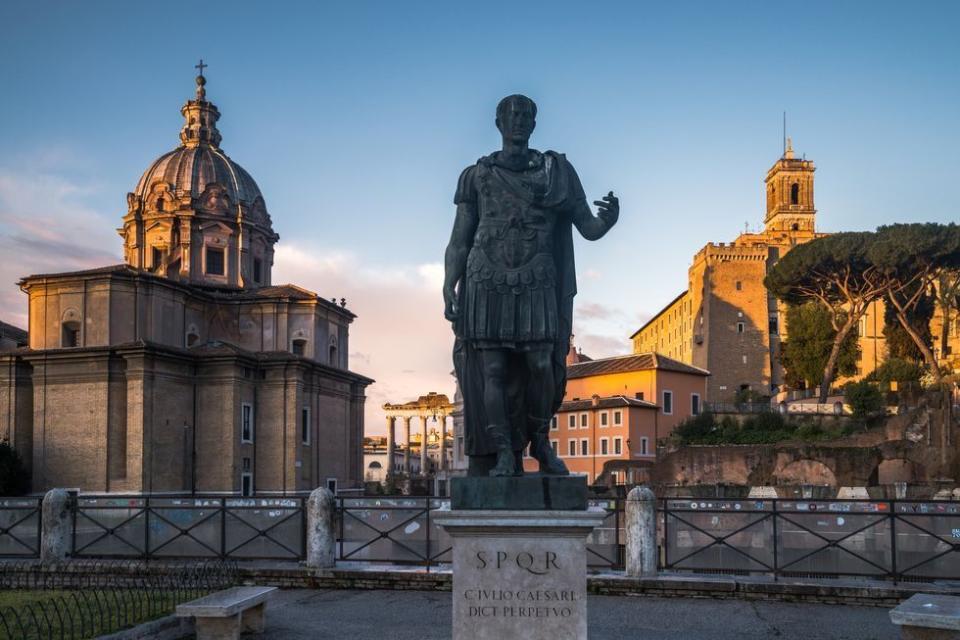 statue of julius ceasar in front of the roman forum, rome, italy, early morning