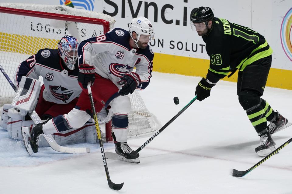 Columbus Blue Jackets goaltender Joonas Korpisalo (70) minds the net as center Boone Jenner (38) defends against pressure from Dallas Stars center Jason Dickinson (18) in the first period of an NHL hockey game in Dallas, Saturday, March 6, 2021. (AP Photo/Tony Gutierrez)