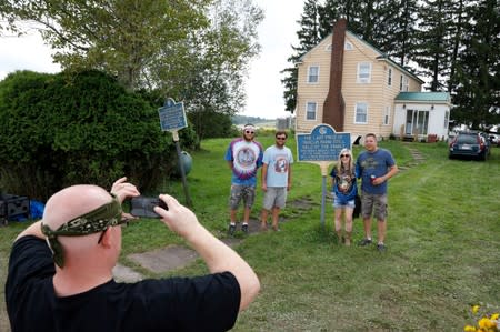 Guests pose by plaques displayed in front of Max and Miriam Yasgur's house during a celebration of the 50th anniversary of the Woodstock Festival in Bethel, New York