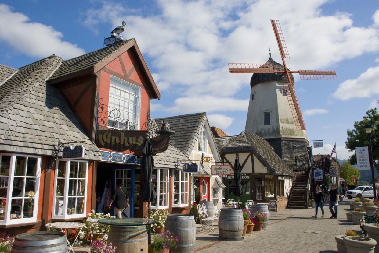 Street of Solvang, California, in May 2016, with people on the boardwalk, cafes, shops and a windmill in the back